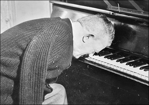 Photo of Billy Collins playing a piano using his nose
