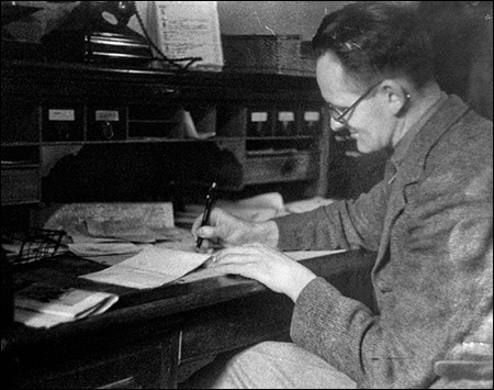Photo of I B Griffith writing at his desk